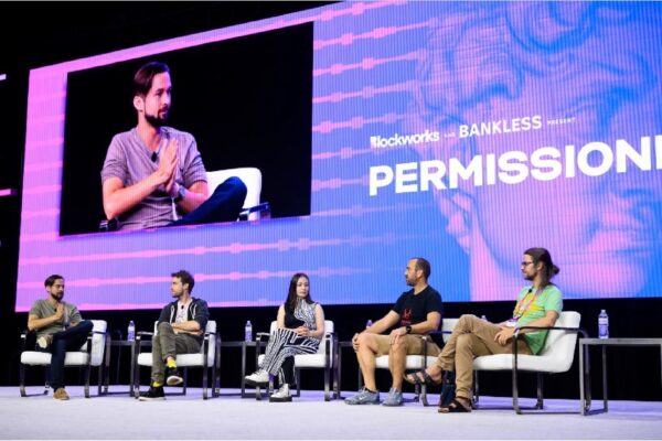 people sitting on chairs on stage at expo group's permissionless event