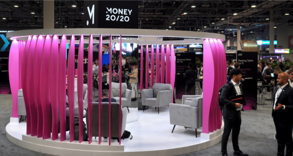 circular trade show booth sitting area with grey chairs surrounded by pink panels