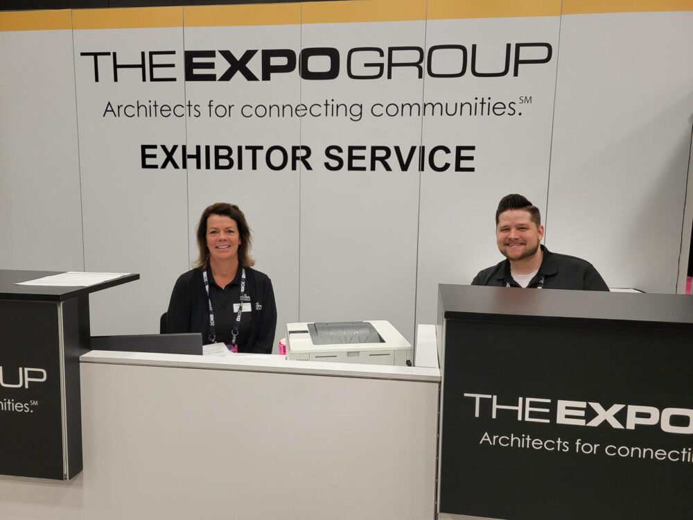 Two expo group employees sitting at an exhibitor serve desk